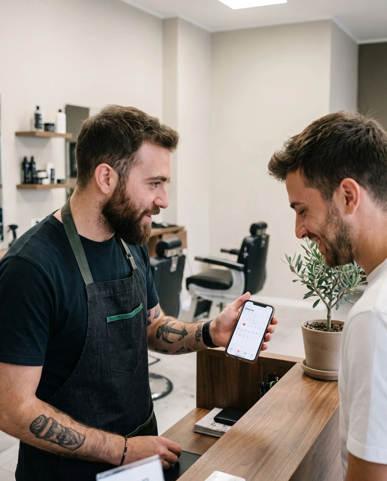 Barbiere al banco mostra il telefono a un cliente sorridente, salone luminoso