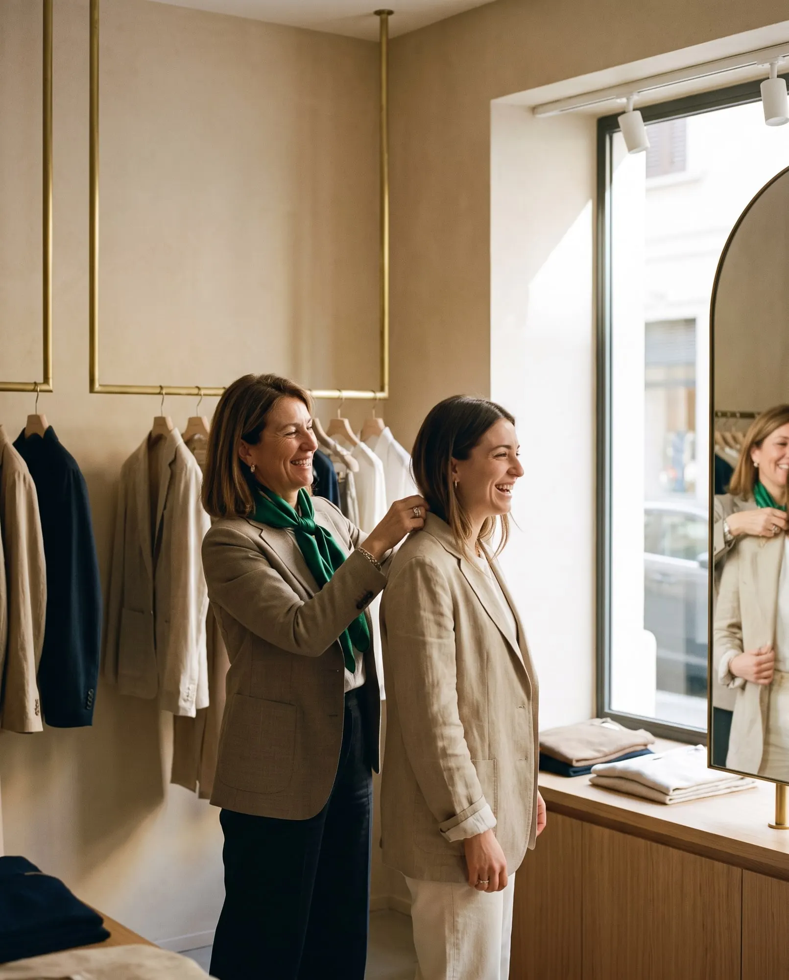 Commessa di una boutique aiuta una cliente a provare una giacca